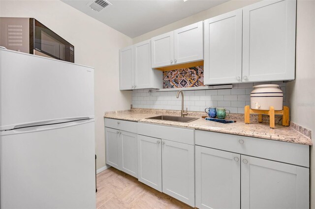 kitchen featuring visible vents, decorative backsplash, freestanding refrigerator, open shelves, and a sink