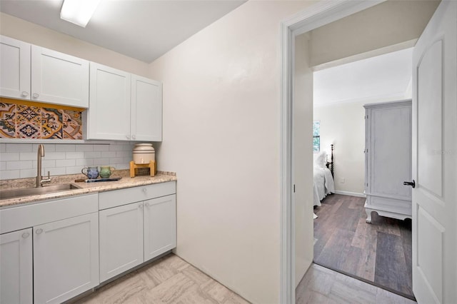 kitchen with light wood-style flooring, a sink, white cabinets, light countertops, and tasteful backsplash