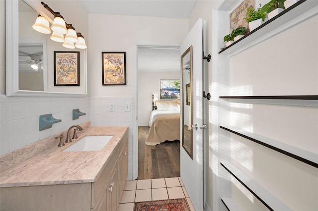 ensuite bathroom featuring tile patterned flooring, connected bathroom, tile walls, and vanity