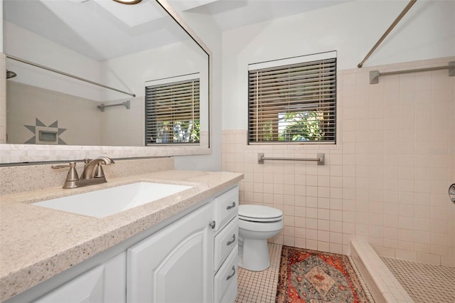 full bathroom with tiled shower, toilet, tile patterned floors, vanity, and tile walls