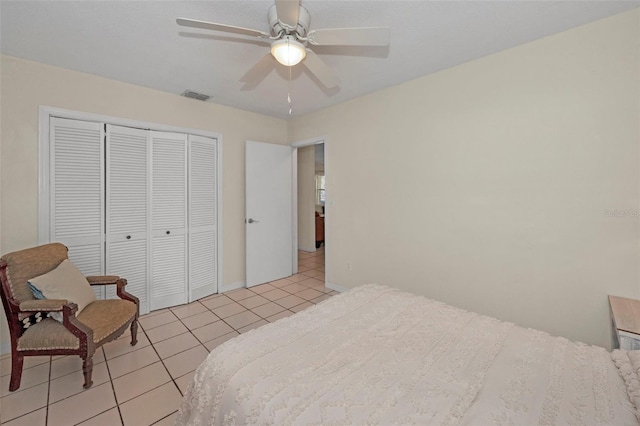 bedroom featuring light tile patterned floors, a closet, visible vents, ceiling fan, and baseboards