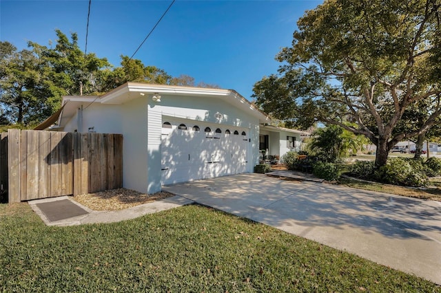 view of front facade featuring an attached garage, fence, concrete driveway, stucco siding, and a front yard