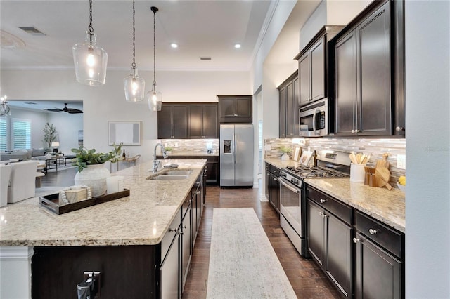 kitchen featuring a large island, sink, stainless steel appliances, tasteful backsplash, and decorative light fixtures