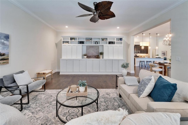 living room with ceiling fan with notable chandelier, wood-type flooring, and ornamental molding