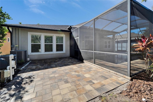 back of property featuring a patio area, glass enclosure, and central air condition unit