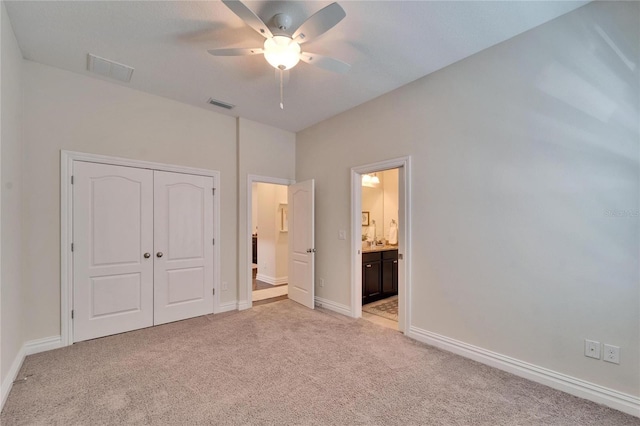 unfurnished bedroom featuring ceiling fan, connected bathroom, light colored carpet, and a closet