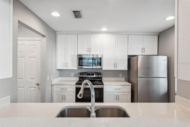 kitchen featuring white cabinetry, appliances with stainless steel finishes, sink, and light stone counters