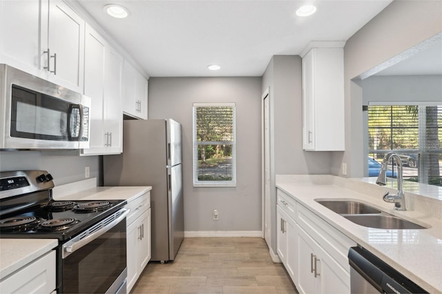 kitchen featuring sink, light hardwood / wood-style flooring, appliances with stainless steel finishes, light stone counters, and white cabinets