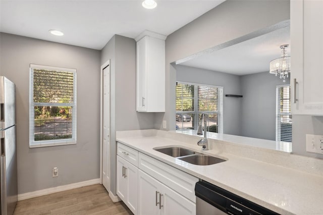 kitchen featuring sink, white cabinetry, stainless steel appliances, light hardwood / wood-style floors, and light stone countertops