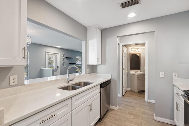 kitchen with stainless steel appliances, white cabinetry, sink, and light hardwood / wood-style floors