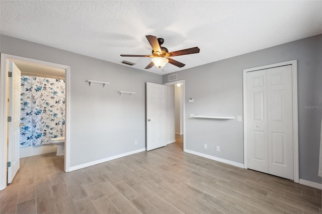 unfurnished bedroom with connected bathroom, light hardwood / wood-style flooring, ceiling fan, a textured ceiling, and a closet