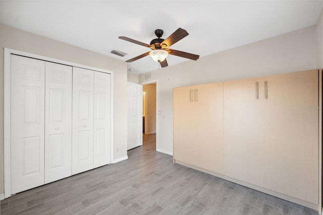 unfurnished bedroom with ceiling fan, light hardwood / wood-style floors, and a closet