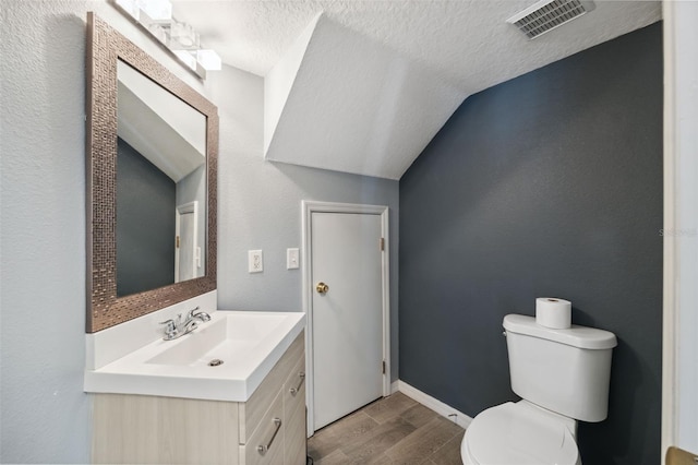 bathroom featuring hardwood / wood-style flooring, lofted ceiling, and a textured ceiling