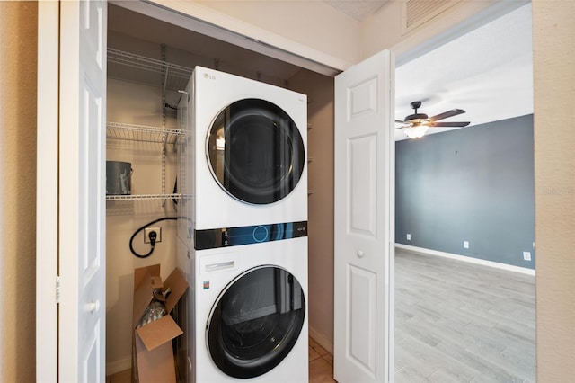 laundry area featuring stacked washer / dryer, ceiling fan, and light hardwood / wood-style flooring