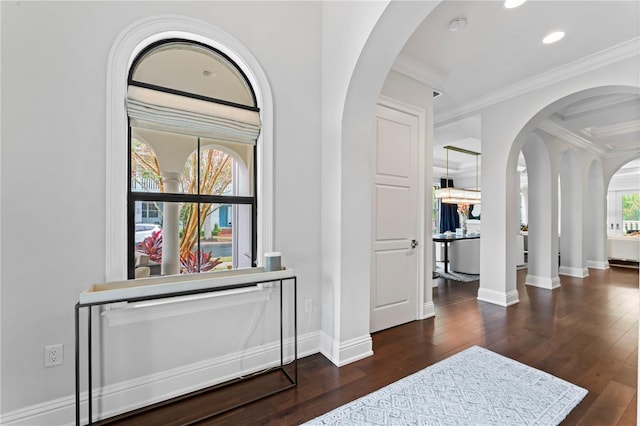 hall featuring wood-type flooring, ornamental molding, arched walkways, and baseboards