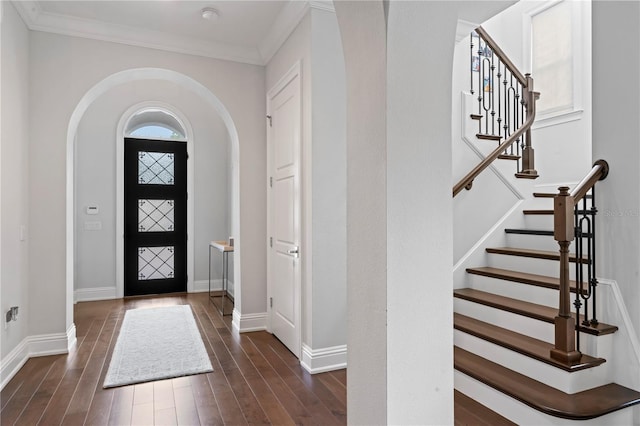 foyer featuring baseboards, arched walkways, dark wood-style flooring, and ornamental molding