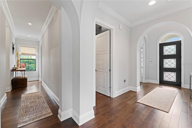 entryway featuring arched walkways, ornamental molding, wood finished floors, and baseboards