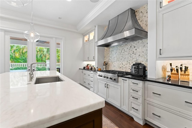 kitchen with a sink, stainless steel gas stovetop, wall chimney exhaust hood, tasteful backsplash, and crown molding