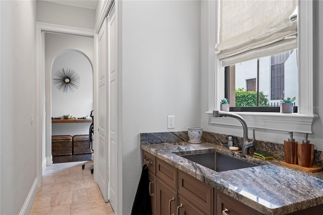 kitchen with dark stone countertops, baseboards, and a sink