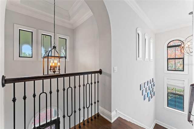 hallway featuring arched walkways, ornamental molding, dark wood-style floors, and a notable chandelier