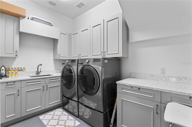 clothes washing area featuring cabinet space, independent washer and dryer, visible vents, and a sink