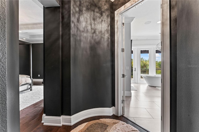 hall featuring crown molding, baseboards, and wood finished floors