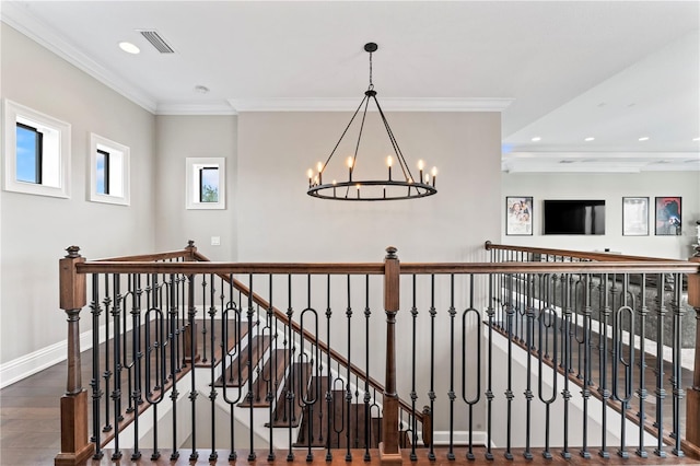 interior space with wood finished floors, an upstairs landing, visible vents, ornamental molding, and an inviting chandelier