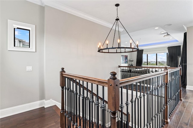 stairway with a tray ceiling, baseboards, wood finished floors, and ornamental molding