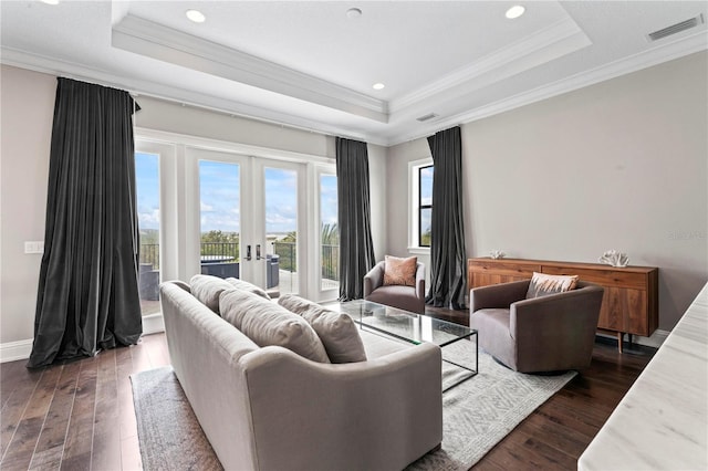 living room with a tray ceiling, visible vents, and dark wood finished floors