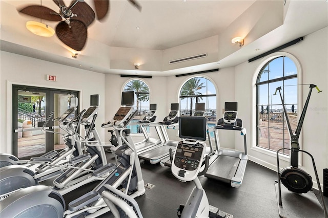 exercise room with baseboards, a raised ceiling, and french doors