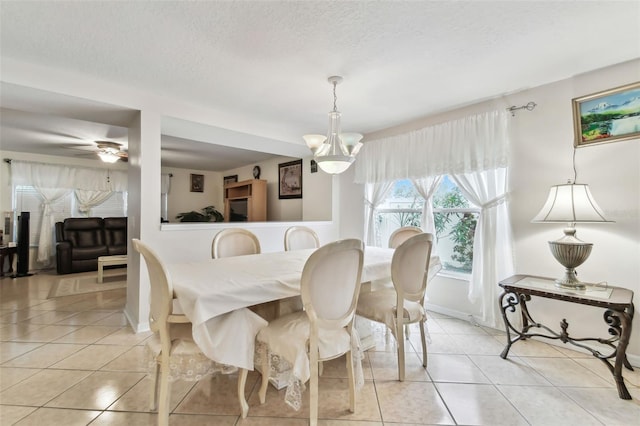 dining space with ceiling fan with notable chandelier, a textured ceiling, and light tile patterned floors