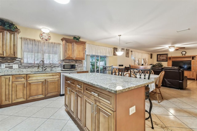 kitchen with light tile patterned flooring, a kitchen island, a breakfast bar, pendant lighting, and sink