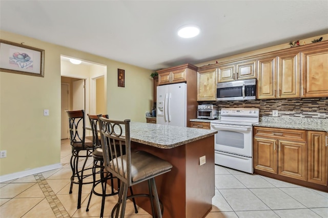 kitchen featuring tasteful backsplash, light stone countertops, light tile patterned floors, and white appliances