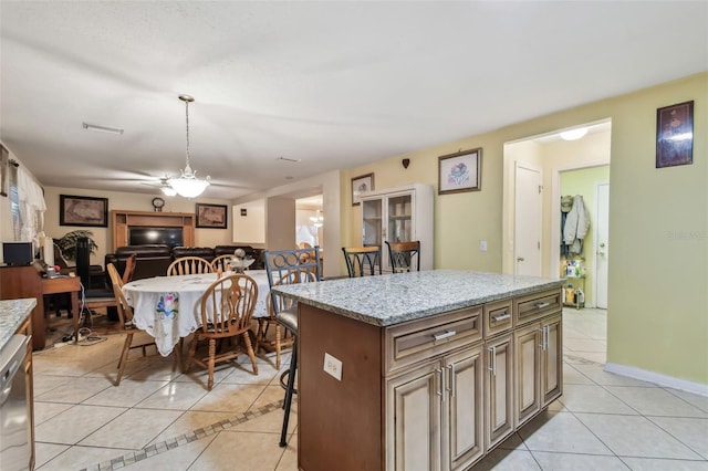 kitchen featuring light tile patterned floors, a center island, light stone countertops, a kitchen bar, and stainless steel dishwasher