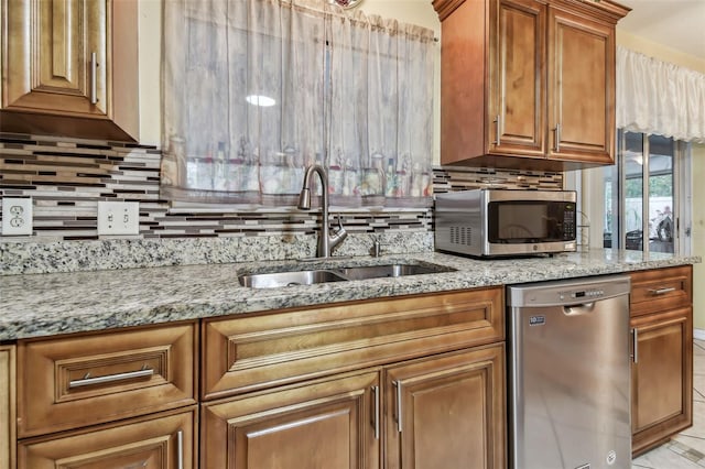 kitchen with light stone counters, appliances with stainless steel finishes, sink, and decorative backsplash