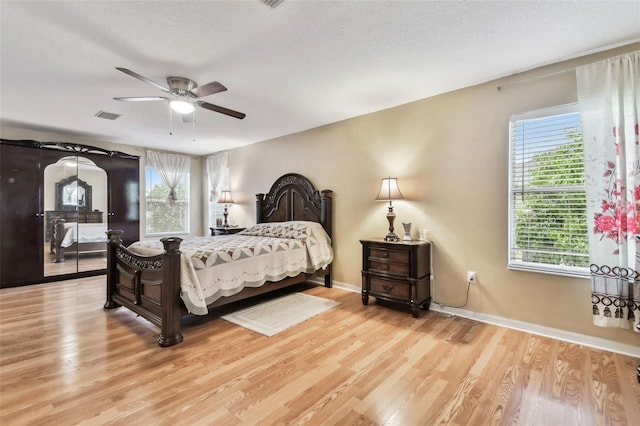 bedroom featuring hardwood / wood-style flooring, ceiling fan, and multiple windows