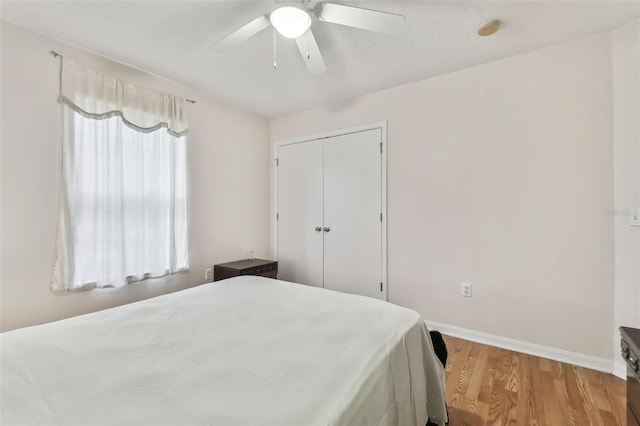 bedroom featuring light hardwood / wood-style flooring, ceiling fan, and a closet