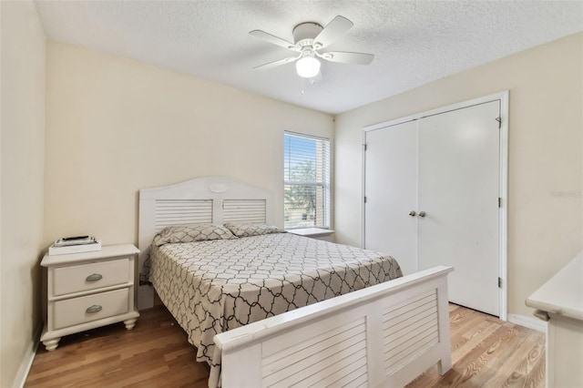 bedroom with a closet, a textured ceiling, ceiling fan, and light hardwood / wood-style flooring