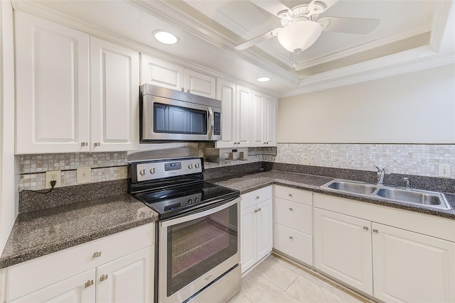 kitchen with sink, backsplash, stainless steel appliances, a tray ceiling, and white cabinets