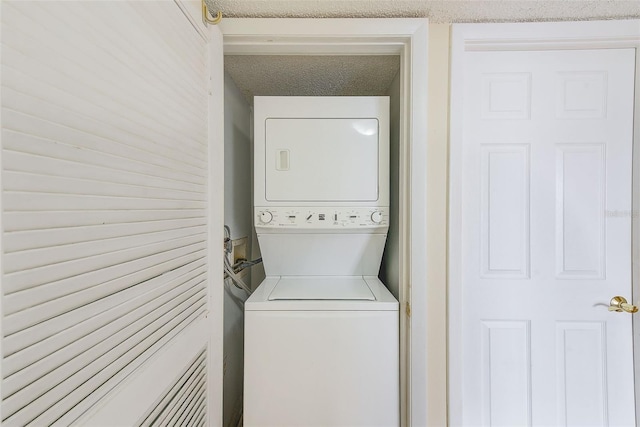 laundry area featuring a textured ceiling and stacked washer / dryer