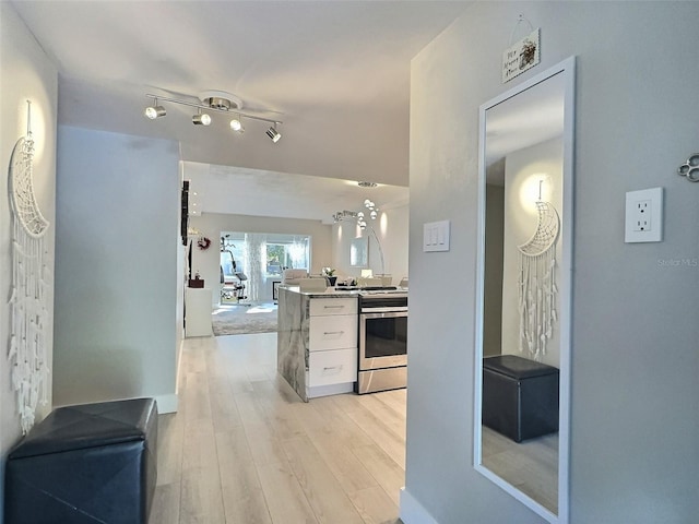 kitchen featuring white cabinetry, stainless steel range with electric cooktop, light wood-type flooring, and kitchen peninsula