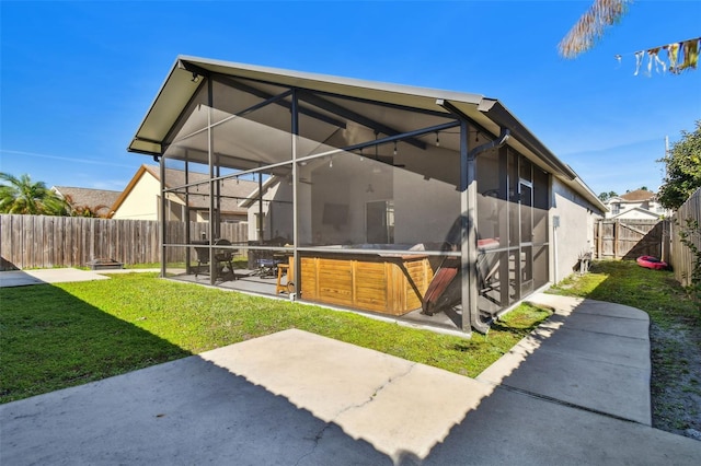 rear view of property with a hot tub, a lanai, a yard, and a patio area