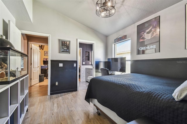 bedroom featuring lofted ceiling, connected bathroom, and light hardwood / wood-style floors