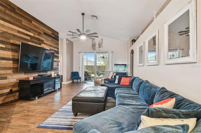 living room featuring hardwood / wood-style flooring, wooden walls, high vaulted ceiling, and ceiling fan