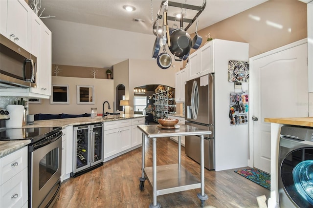 kitchen featuring wine cooler, sink, appliances with stainless steel finishes, washer / clothes dryer, and white cabinets