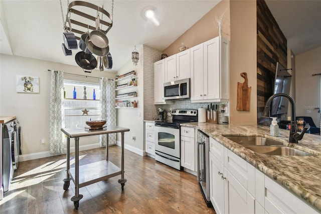 kitchen with sink, vaulted ceiling, appliances with stainless steel finishes, light stone countertops, and white cabinets