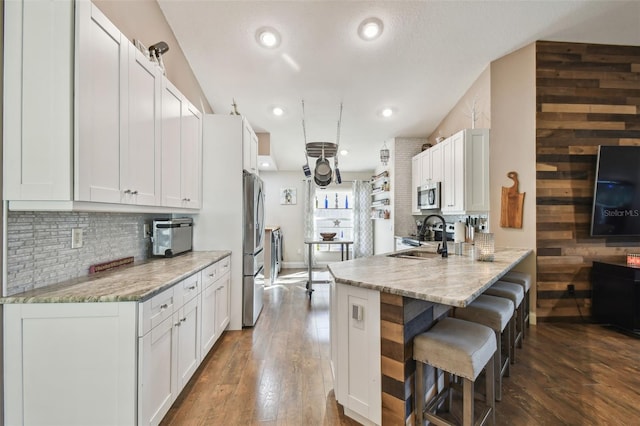 kitchen with dark hardwood / wood-style floors, white cabinetry, sink, stainless steel appliances, and light stone countertops