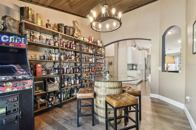 bar featuring an inviting chandelier, wooden ceiling, dark hardwood / wood-style floors, and stainless steel refrigerator