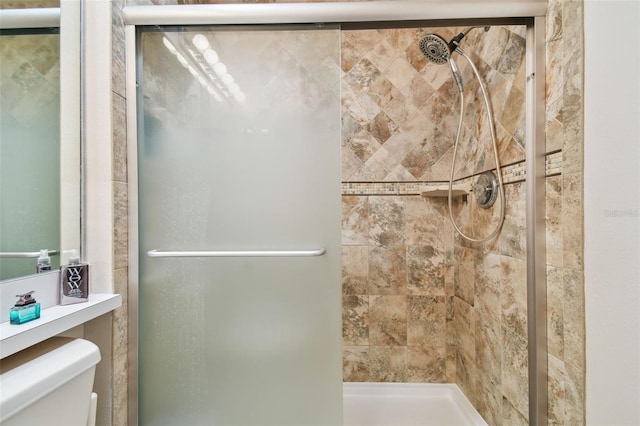 bathroom with a shower with shower door and toilet