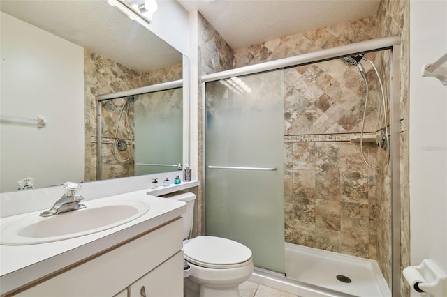 bathroom with a shower with door, vanity, tile patterned flooring, and toilet